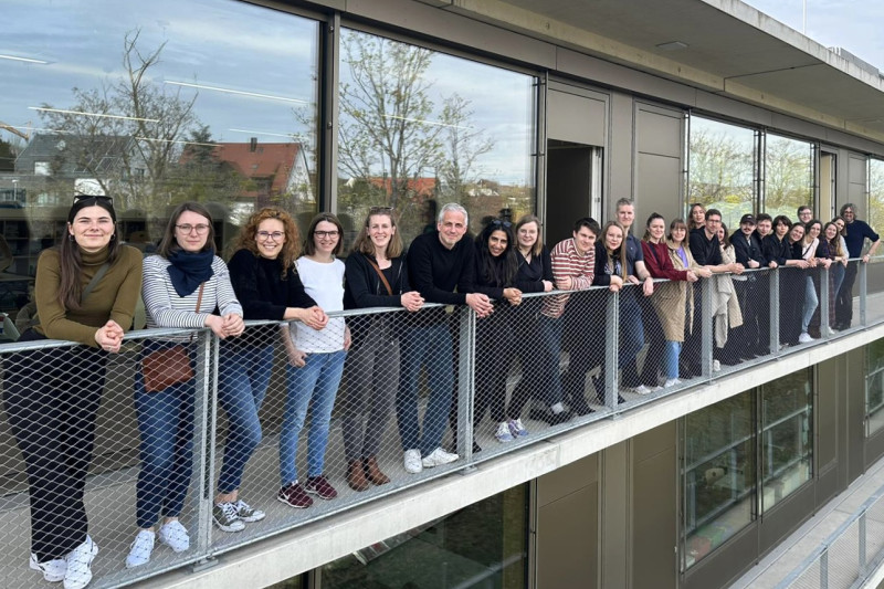 Gruppenfoto einer Büroexkursion in Stuttgart, Teilnehmer stehen lächelnd auf einem Balkon.