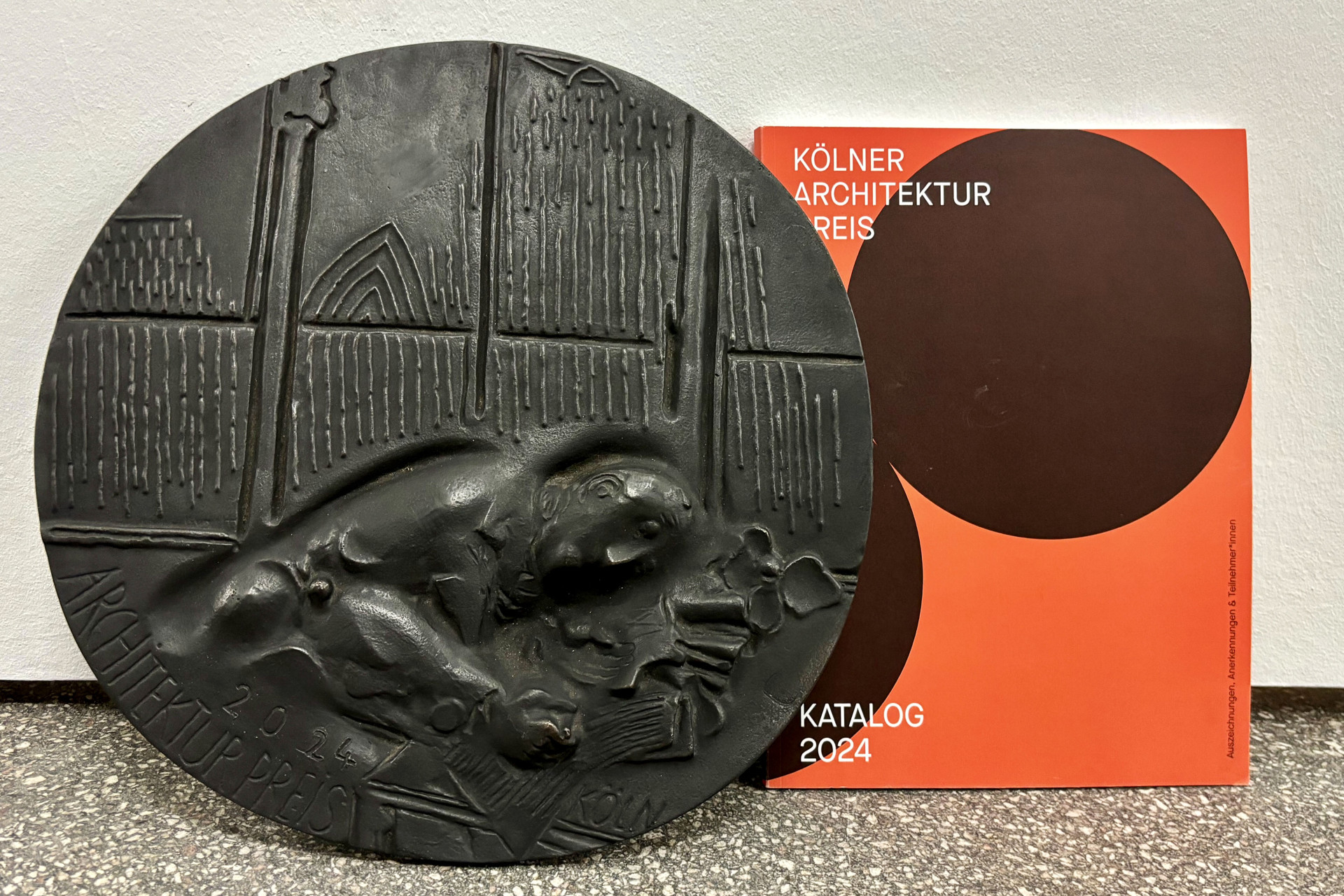 Bronzeplatte mit Relief und Katalog des Kölner Architekturpreises 2024.