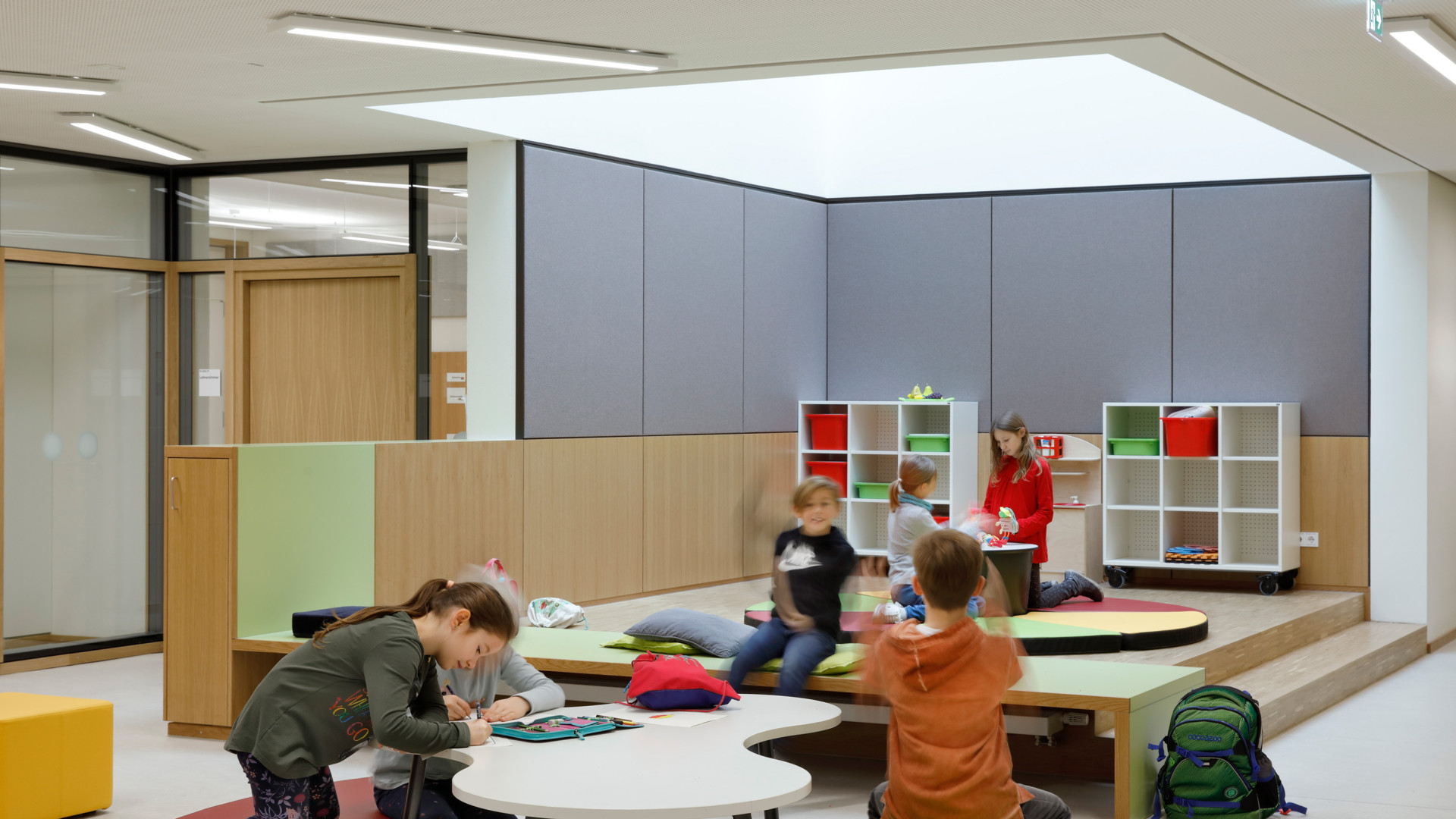 Kinder in einem modernen Klassenraum, kreativ tätig an Tischen und Sitzflächen.