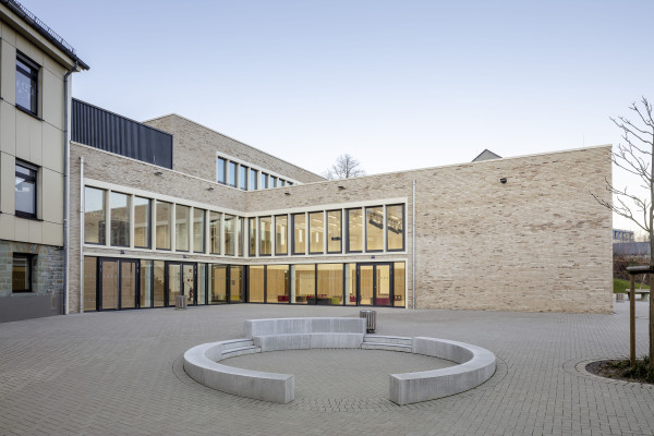 Außenperspektive zeigt den Blick auf den Schulhof und den Neubau der Schule.