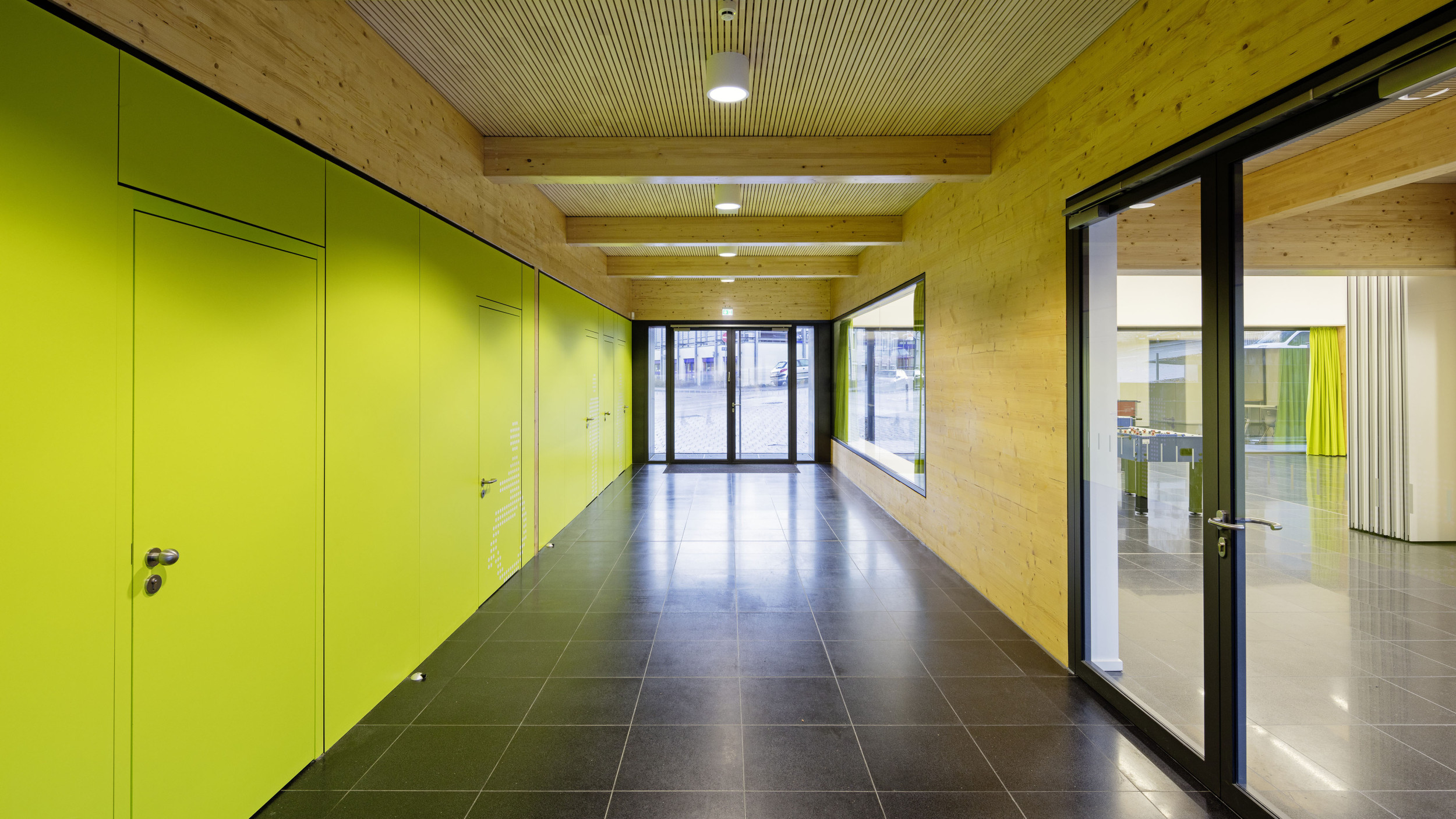 Innenperspektive von einer grünen und einer holzvertäfelten Wand, die den Eingangsbereich definieren.
