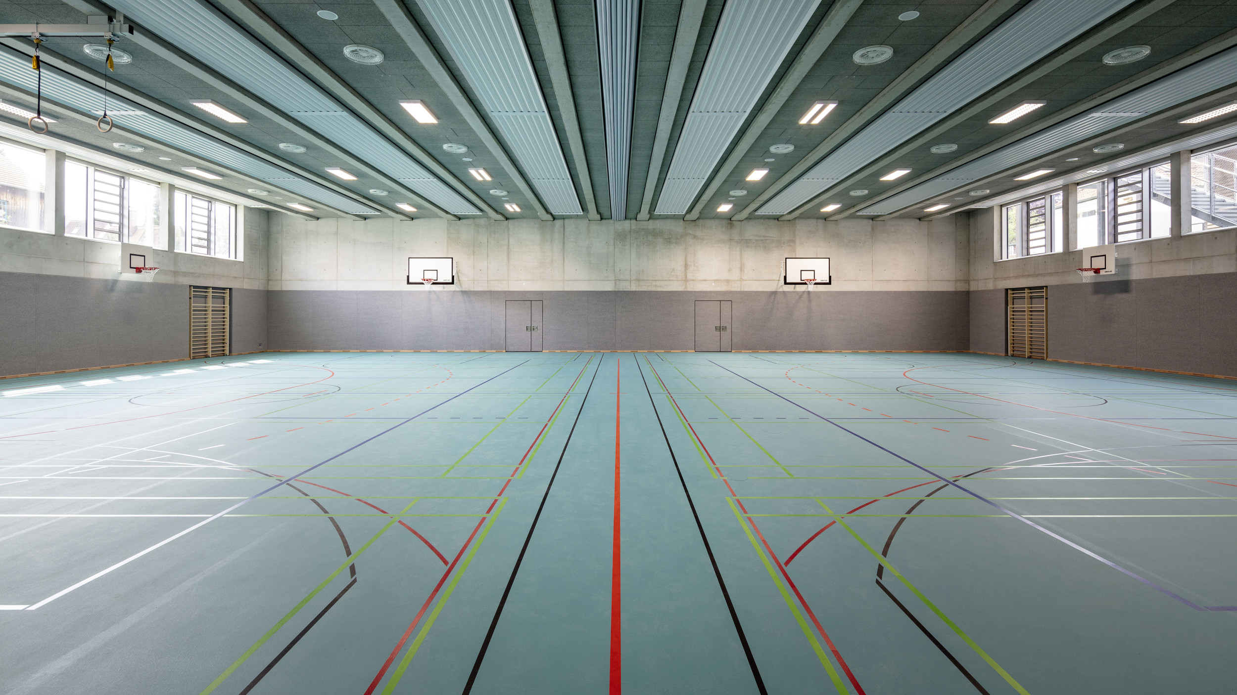 Innenperspektive der Sporthalle mit einem türkisen Hallenboden.