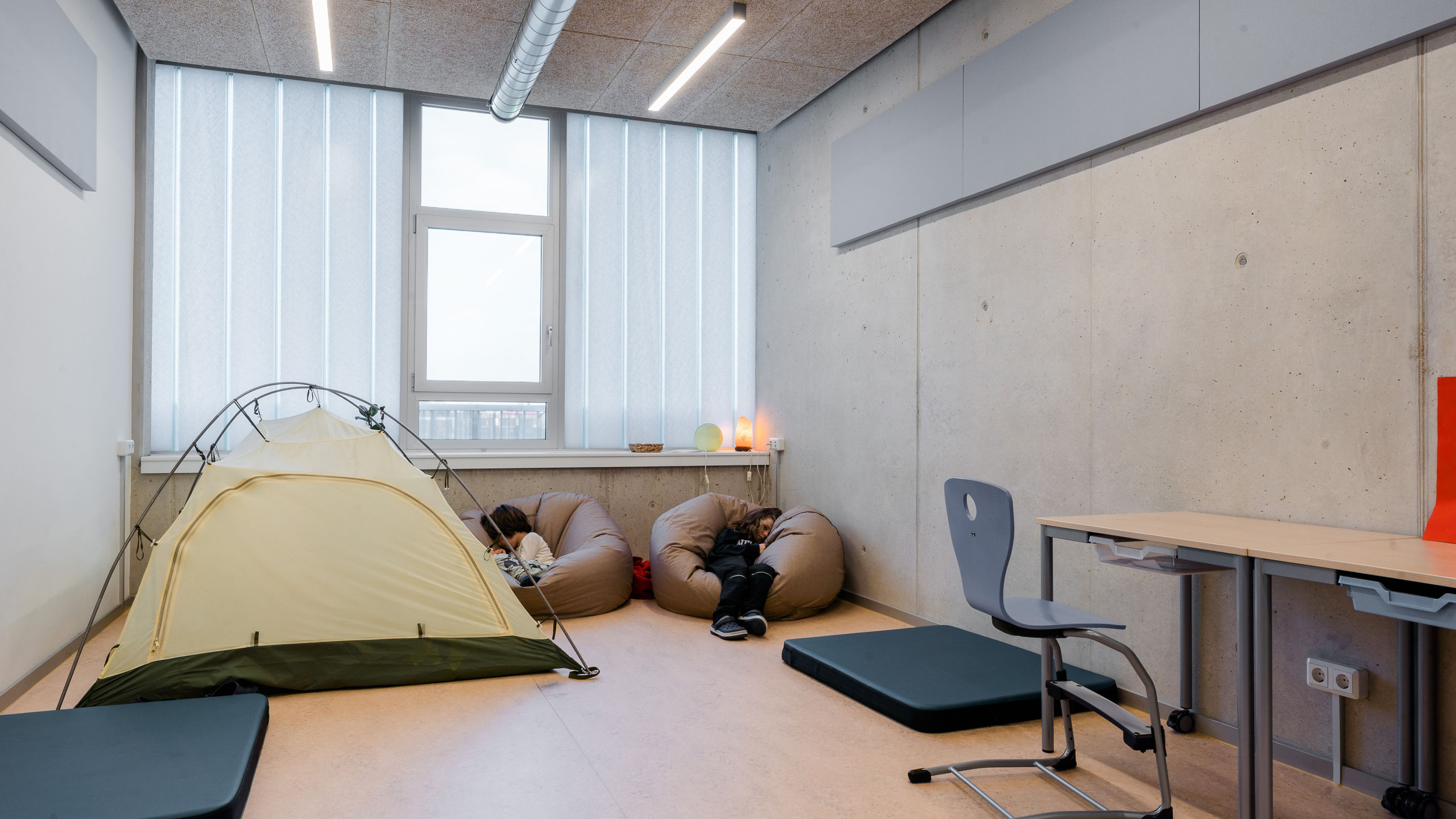 Innenperspektive zeigt Schüler:innen, die sich mit Zelten und Sitzsäcken einen Ruhebereich innerhalb des Raumes geschaffen haben.